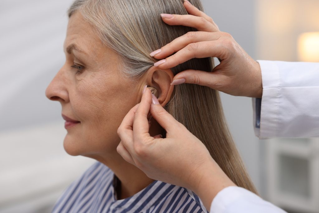 An elderly woman having a hearing aid fitted.