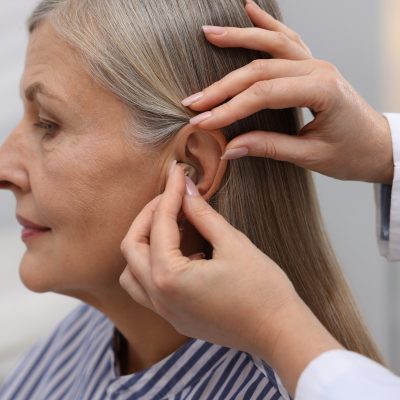 An elderly woman having a hearing aid fitted.