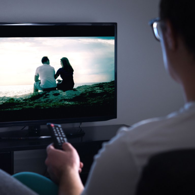 A man watching a film on his TV.