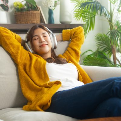 Young woman listening to music sitting on her sofa.