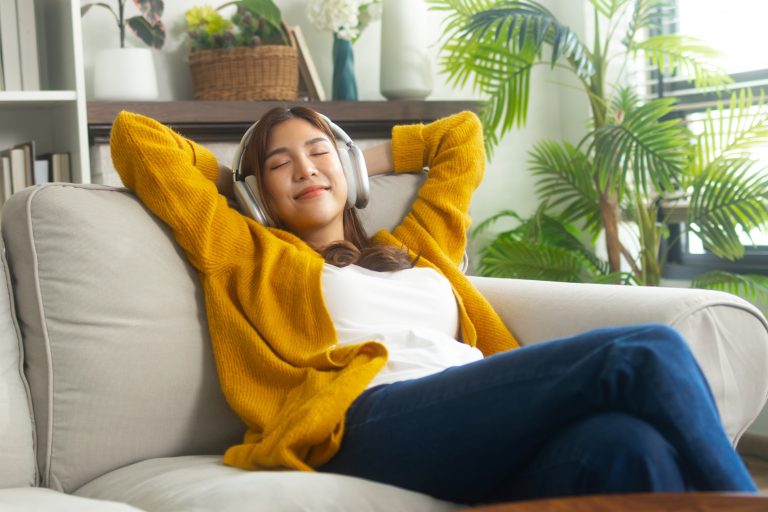 Young woman listening to music sitting on her sofa.