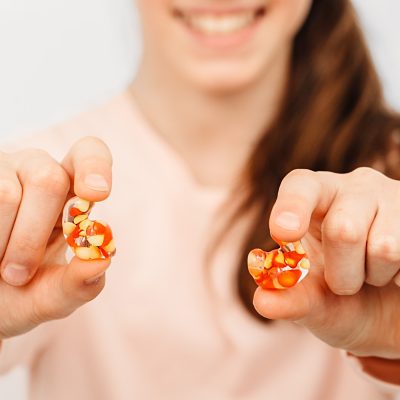 A close-up view of custom-molded earplugs being held by a young girl, with a blurred background focusing attention on the earplugs.