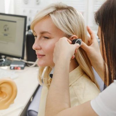 An audiologist examining a patient's ear using an otoscope during a hearing check-up.