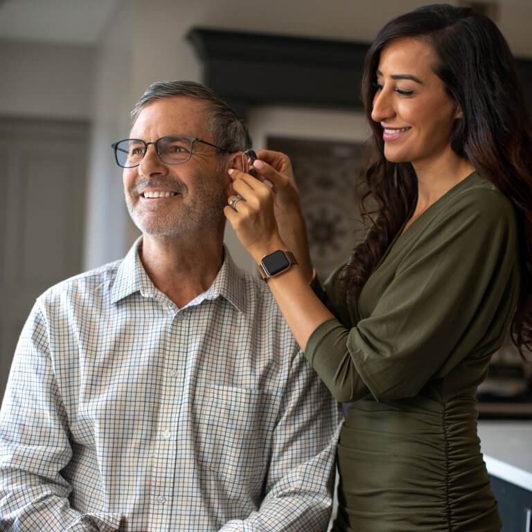 An audiologist fitting a hearing aid in a patient's ear.