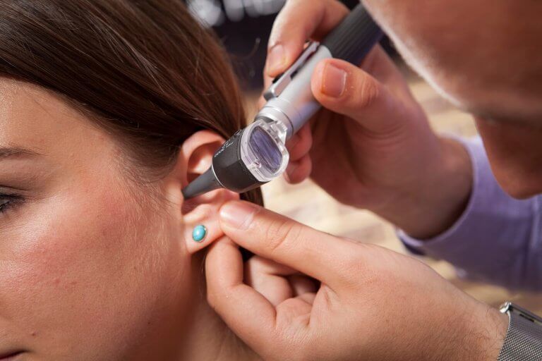 An audiologist examining the ear of a patient with an otoscope.