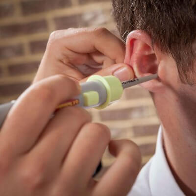 An audiologist performing water irrigation on a patient for ear wax removal.