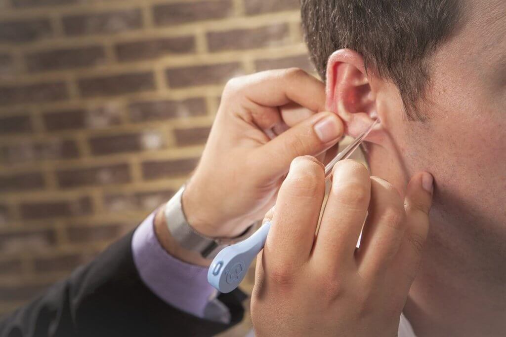 An ear doctor removing wax from a patient's ear.