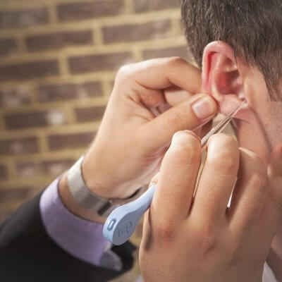 An ear doctor removing wax from a patient's ear.