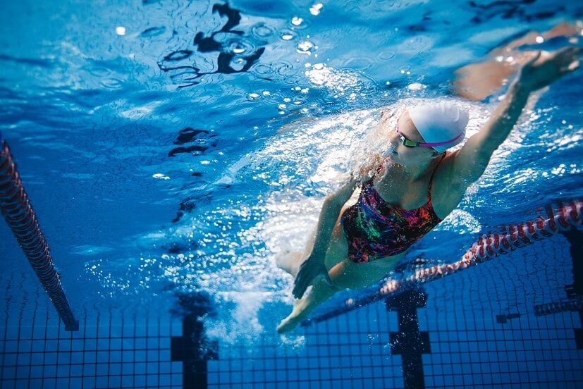 A girl swimming front crawl in a public swimming pool.