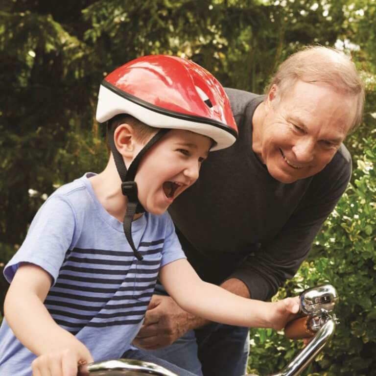 A grandfather teaching his grandson how to ride a bike and playing with him.