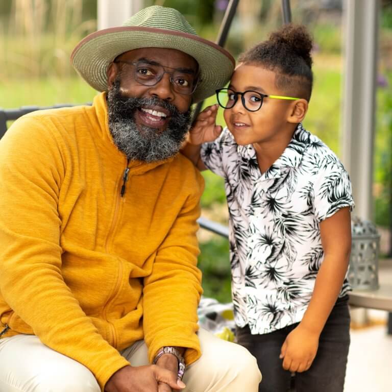 A grandson whispering to his grandpa's ear.