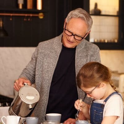 A grandpa and his granddaughter having tea.