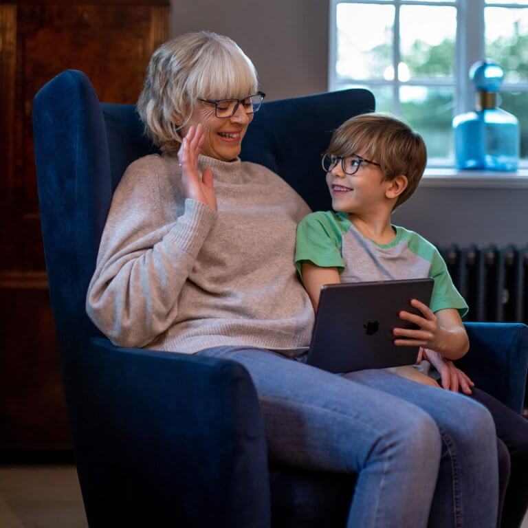 A grandma and grandson wearing glasses and talking on the tablet.