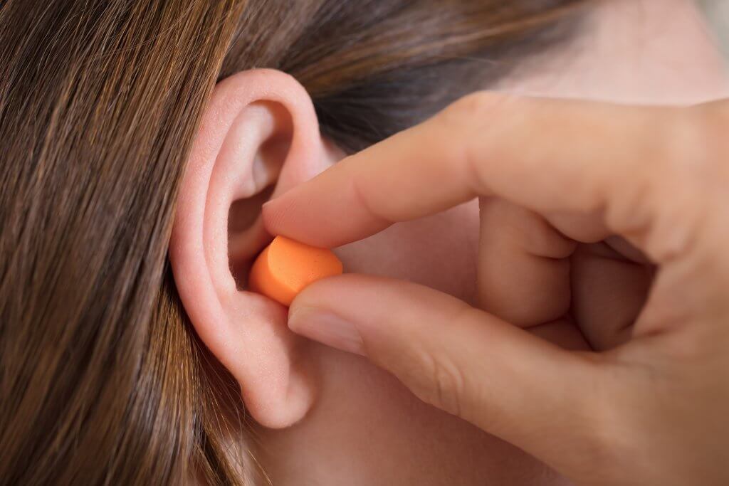 A woman putting on ear protection.