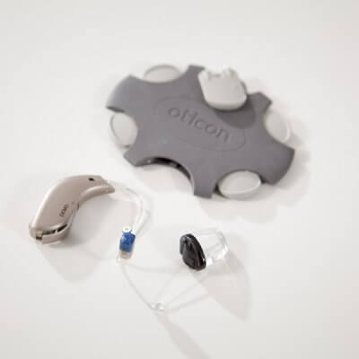 Oticon 'No Wax' wax guards next to a hearing aid.
