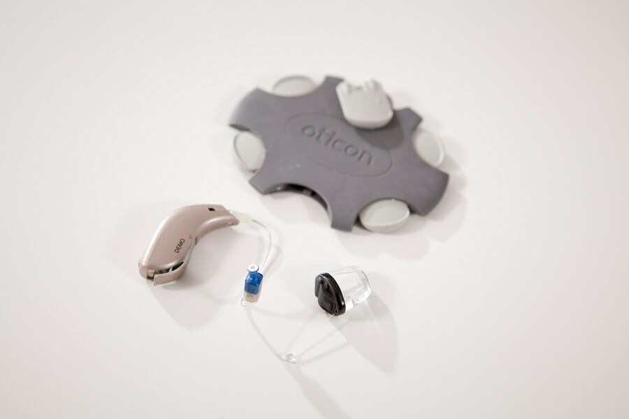 Oticon 'No Wax' wax guards next to a hearing aid.