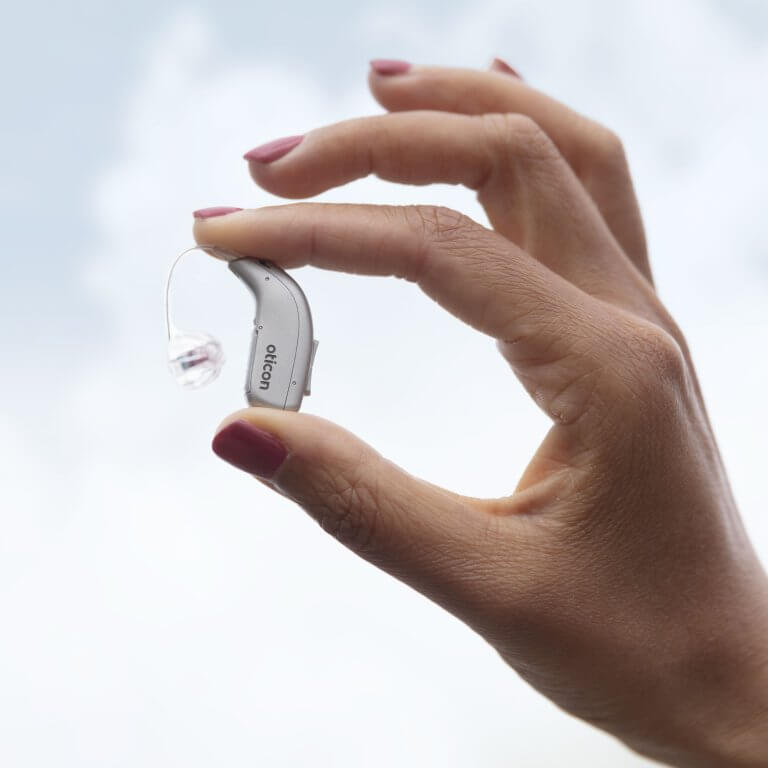 A woman holding a hearing aid in her hand.