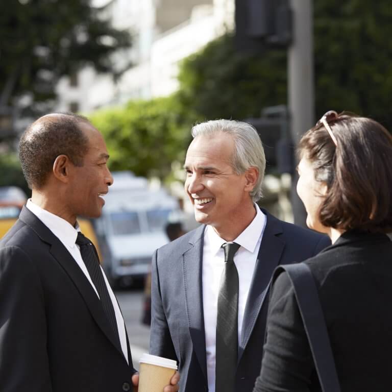 People wearing suits talking in the street.