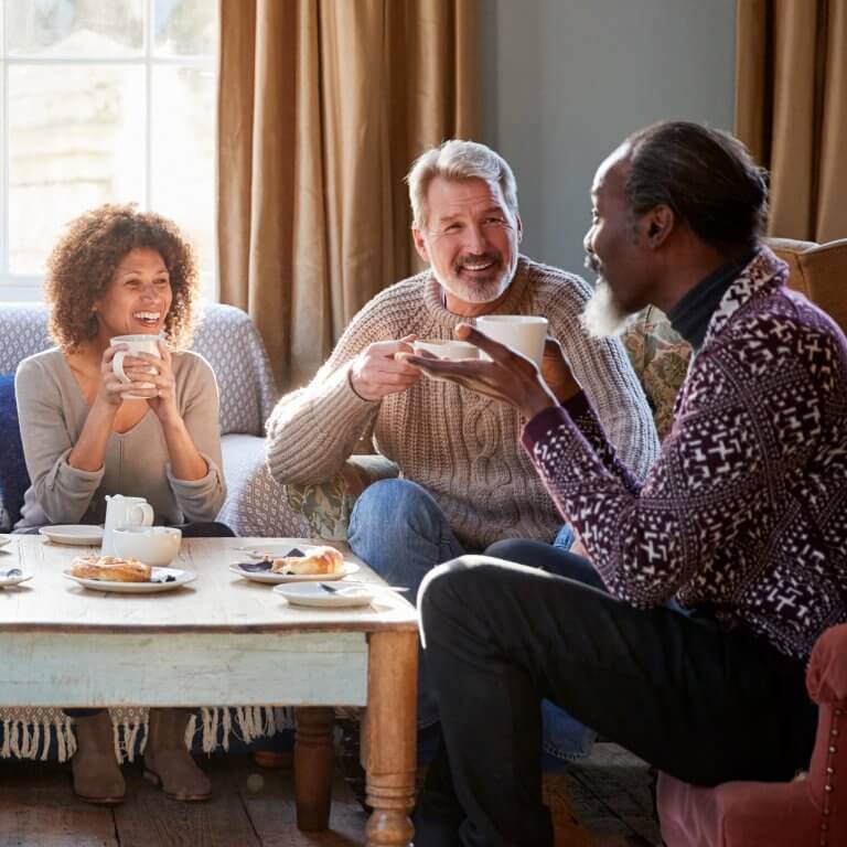 Three people having tea in a living room.