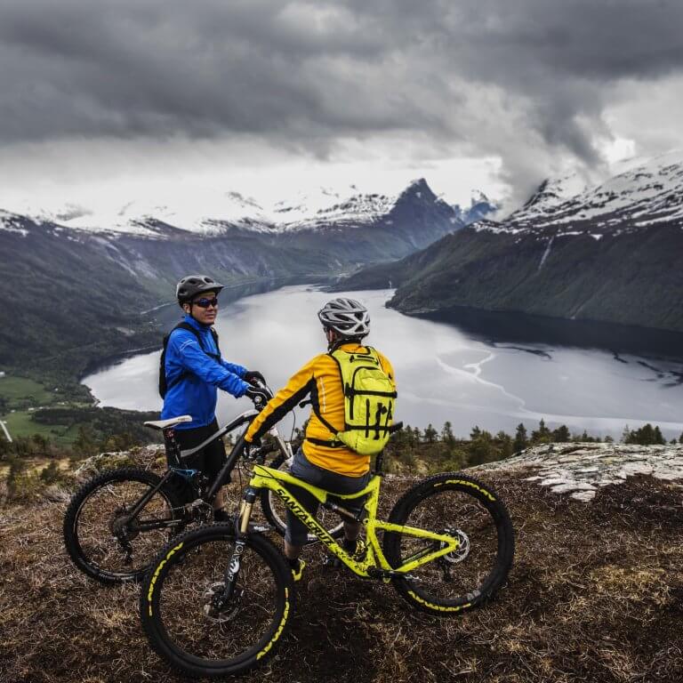 Two people resting after biking in front of a iced lake.