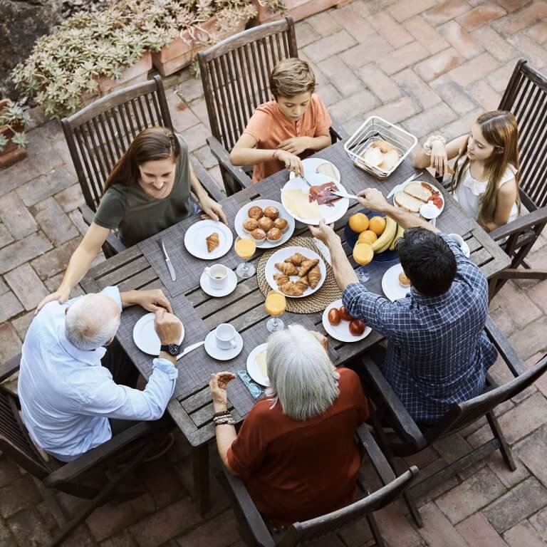 A family having breakfast outside around a table.