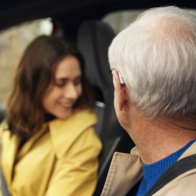 A man wearing a hearing aid in a car.