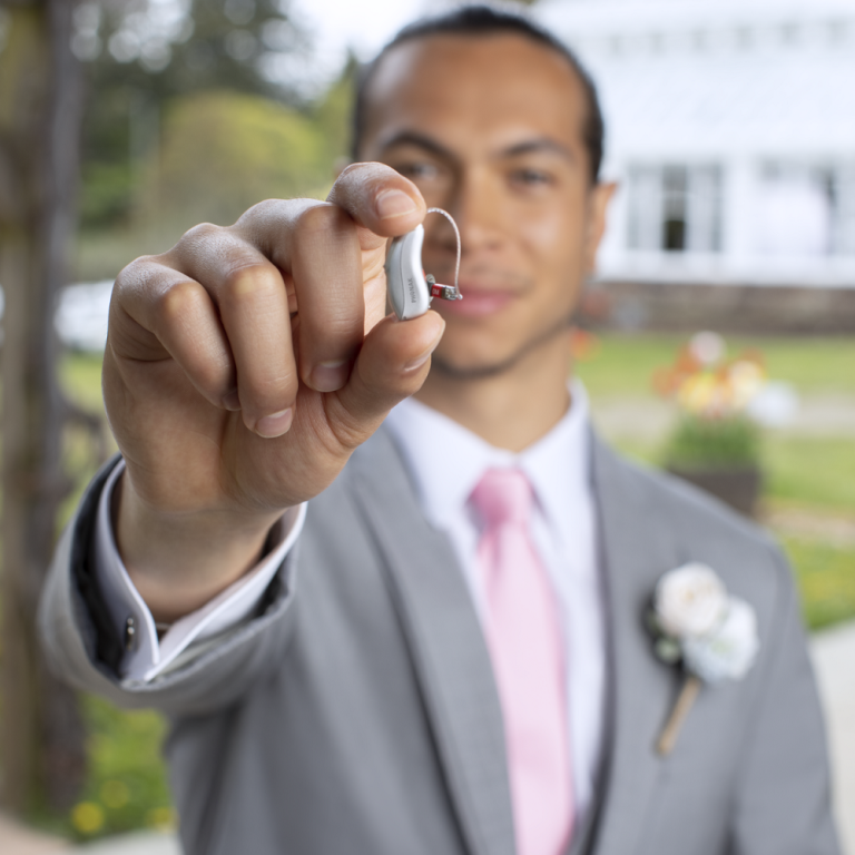 Someone holding Phonak Audéo Lumity hearing aids in their hand.