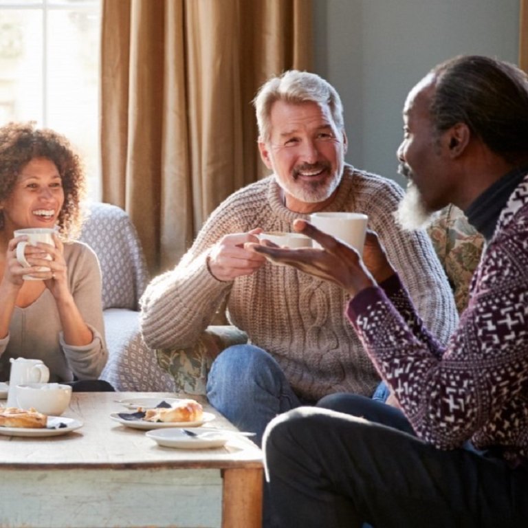 Three people having tea in a living room.