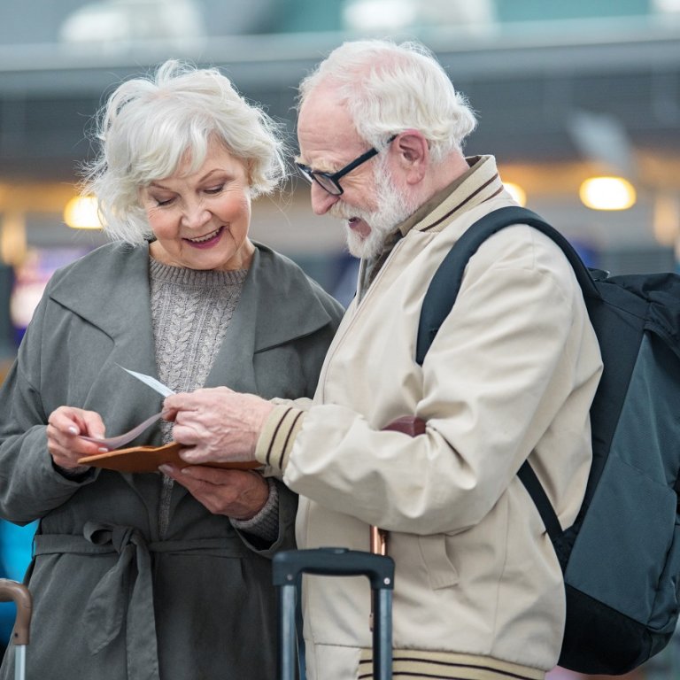 A couple at the airport looking at their their flight tickets.