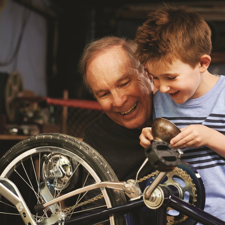 A grandpa and his grandson fixing a bike.