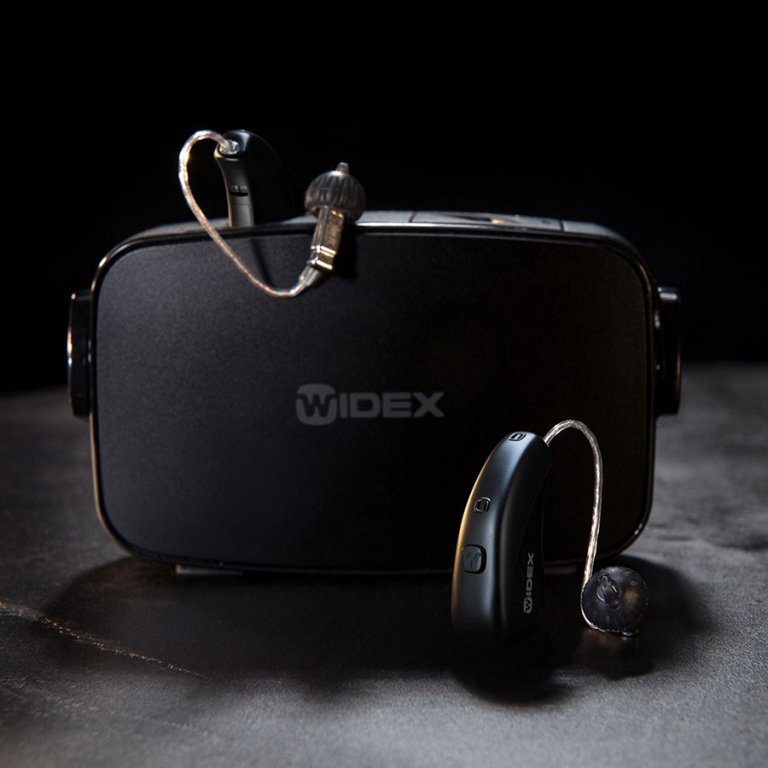 Widex hearing aids with their charging doc.