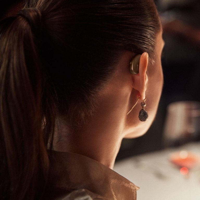 A woman wearing a widex hearing aid.