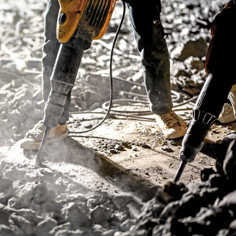 A man using a jackhammer on the floor.