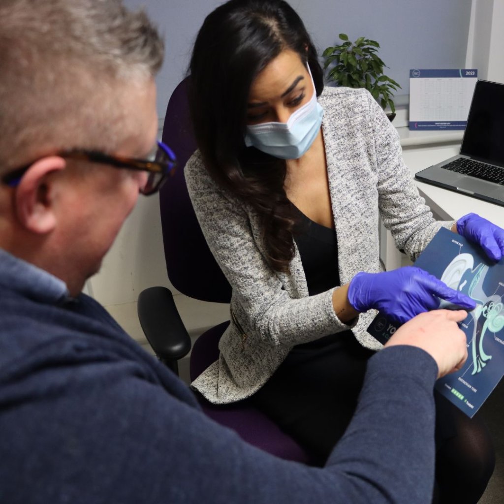 An audiologist explaining an ear issue to a patient.