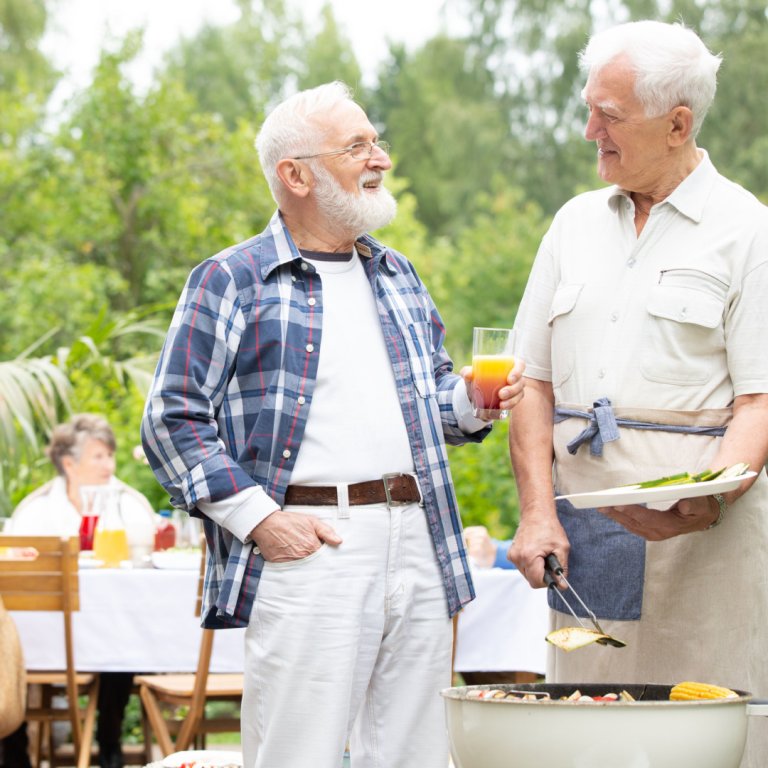 Two elderly people talking during a barbecue.