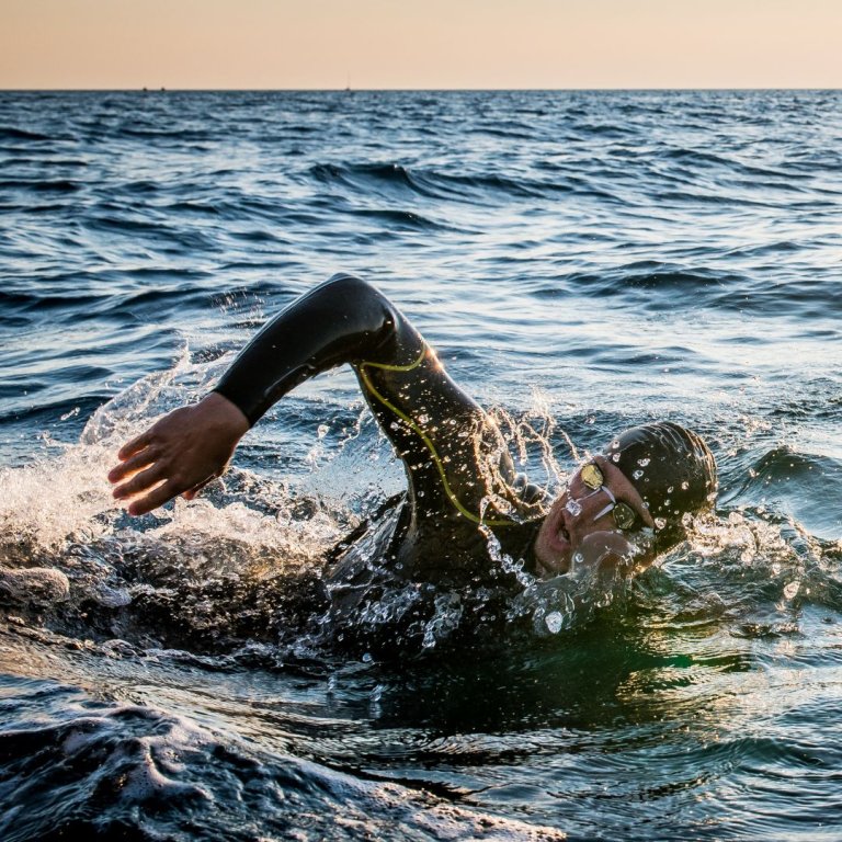 fresh water swimmer in wetsuit, goggles and swimming cap.