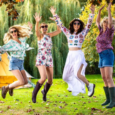 Four women jumping in the air in front of a tent.