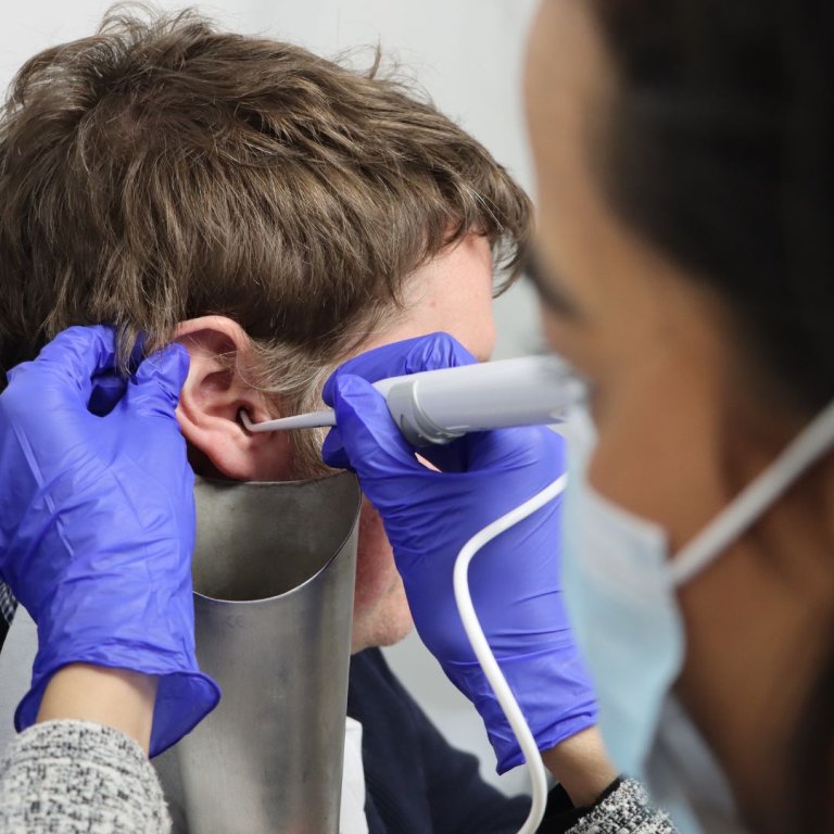 A wax removal clinician using water irrigation on a patient.