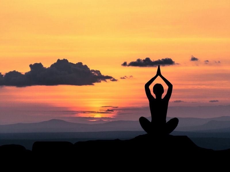 A person practicing yoga at sunset.