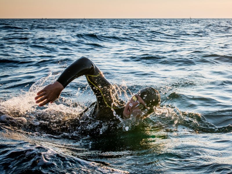 Person in a wetsuit, swimming front crawl in the sea.