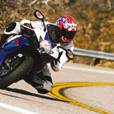 A person riding a blue and white motorcycle on a bend.