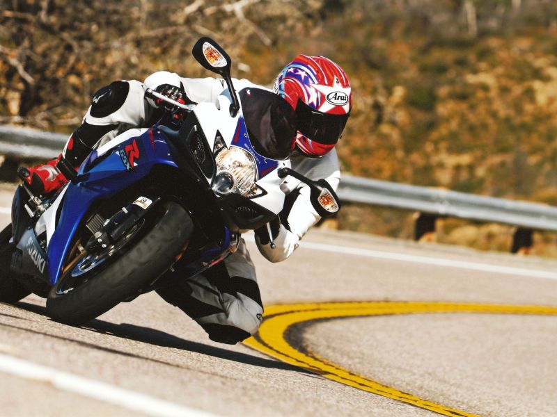 A person riding a blue and white motorcycle on a bend.