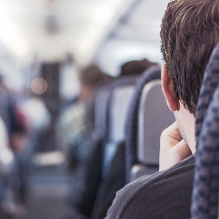 A man on sat on the aisle seat of a plane.