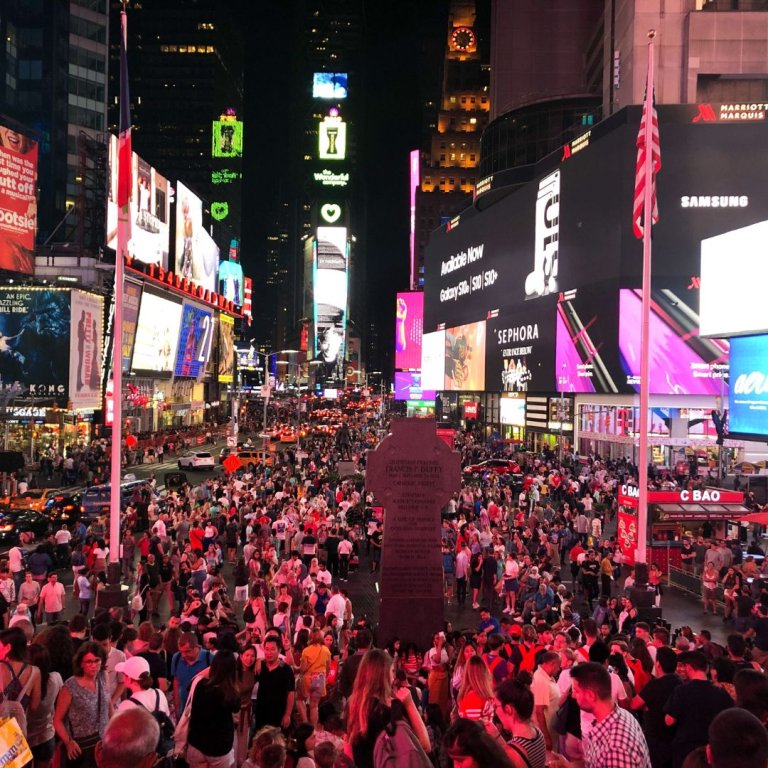 Times Square, New York, full of tourists at night.