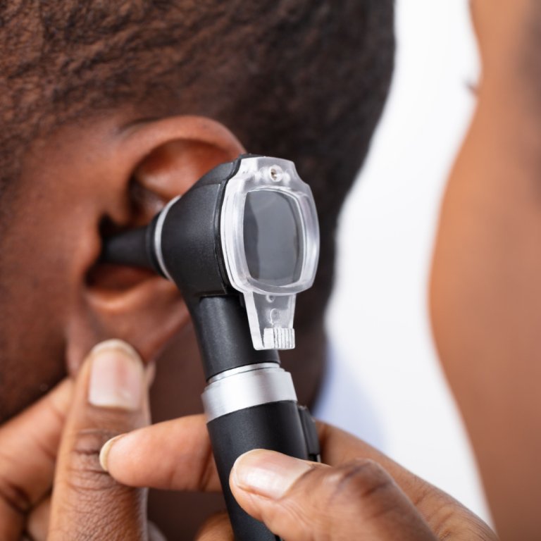 An audiologist examining the ear of a patient with an otoscope.