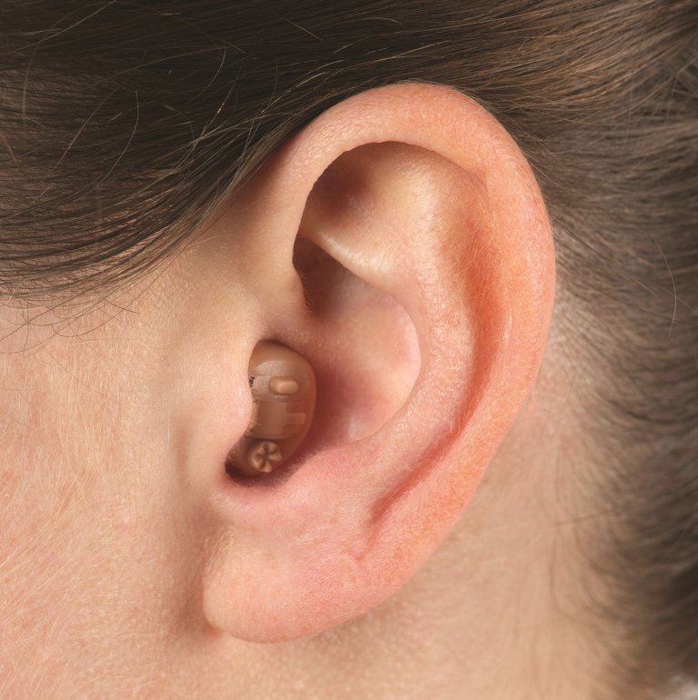 Close-up on a person's ear wearing an in-the-canal (ITC) hearing aid.