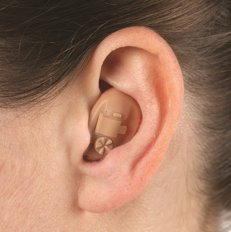 Close-up on a person's ear wearing an in-the-ear (ITE) hearing aid.