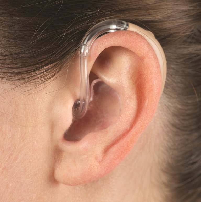 Close-up on a person's ear wearing a behind-the-ear (BTE) hearing aid.