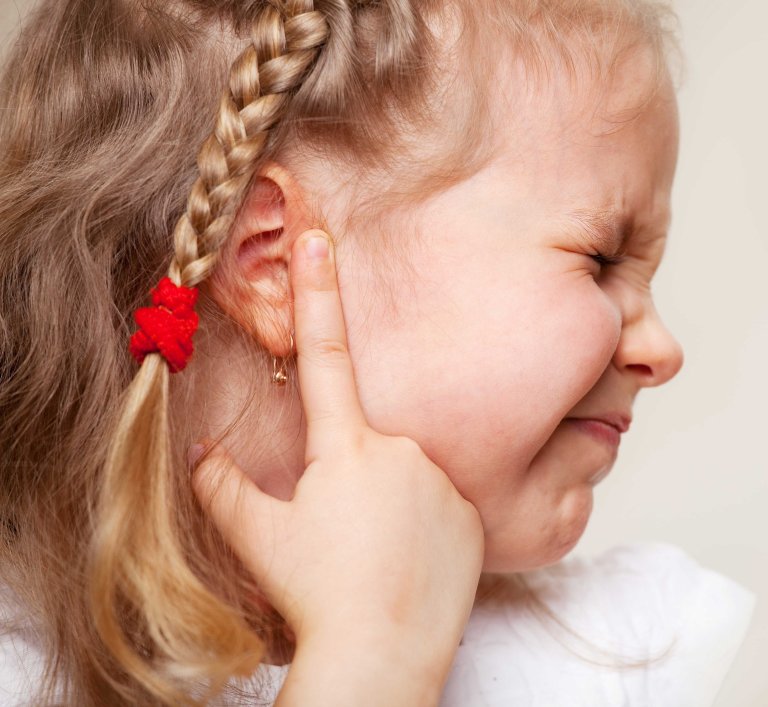 A child being in pain and holding her ear.