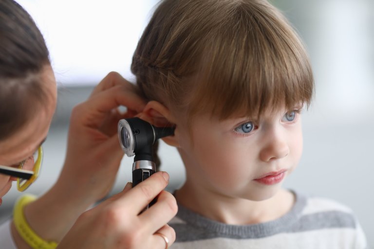 An audiologist checking the ear of a child.